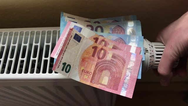 Steigende Heizkosten symbolisiert durch Geldscheine auf Heizung