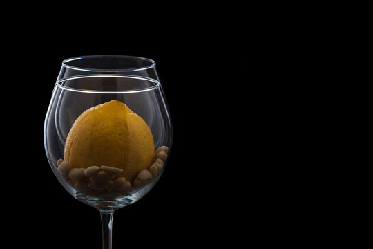 a glass on a black background, peanut and lemon, the contour of the glass with lemon and peanuts. the theme of healthy eating, lemon water and peanuts.