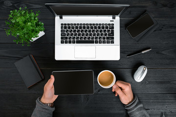 Hipster black wooden desktop top view, male hands typing on a laptop