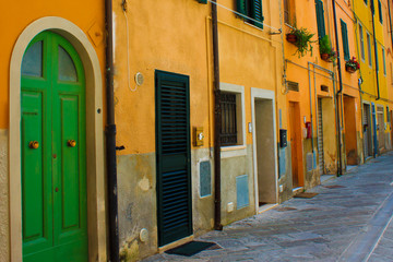 Bright narrow street with yellow houses in traditional Italian style. Green door on the frontview
