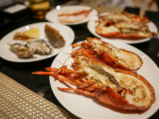 Giant grilled river prawns, Rock Lobster, Oysters, and Crab legs on the white dishes.