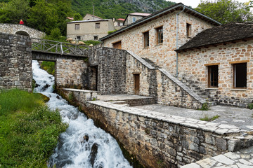 Fototapeta na wymiar Traditional stone houses and two small bridges near a small cascade in Anthochori village in Epirus, Greece
