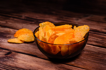 Potato chips in glass bowl on wooden table