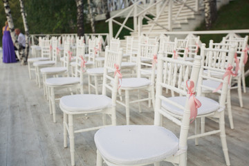 White chairs decorated with pink ribbons