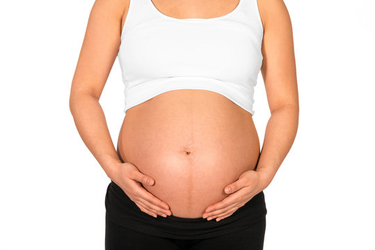 Pregnant woman embracing her bare belly with white background