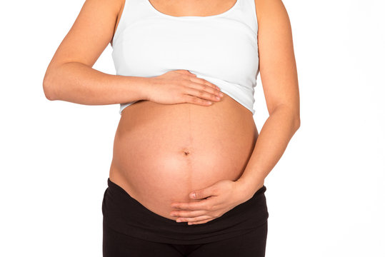Pregnant woman embracing her bare belly with white background