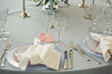 Crystal glasses stand at dinner plate with white serviette on it