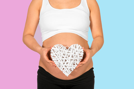 Pregnant woman holding heart with pink and blue background
