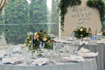 Tables covered with blue cloth and decorated with candles and flowers stand in the restaurant
