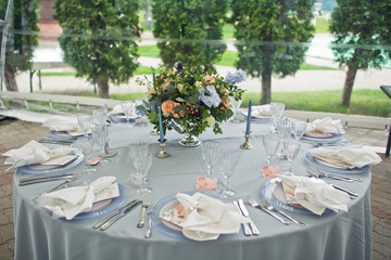 Little bouquet with orange roses and blue flowers stands on round blue table