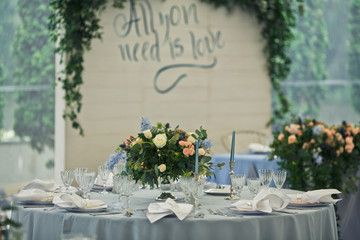 Round table covered with blue cloth and decorated with roses stands in the restaurant