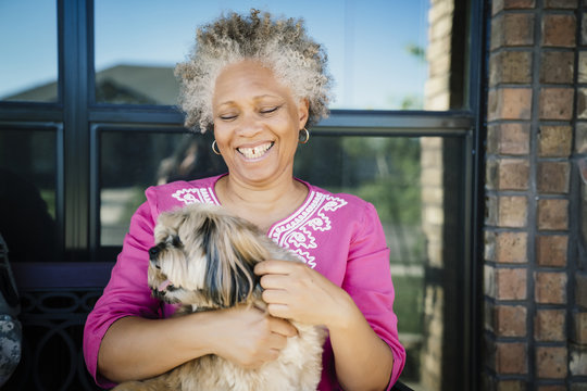 Black woman hugging dog near window