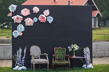 Cosy chairs stand before black board with cloth flowers prepared for the pictures