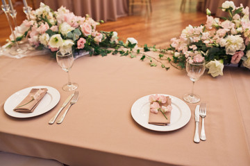 Beige serviettes with orchids lie on white plates on dinner table