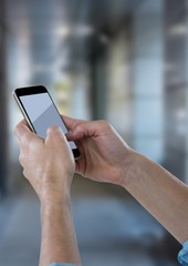 Hands with phone against blurry hallway