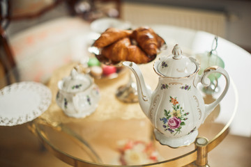 Teapot with flower design stands on the little table