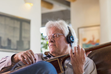 Caucasian man listening to headphones and playing guitar