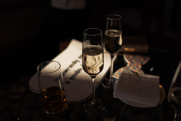 Champagne flutes stand in the darkness on dinner table