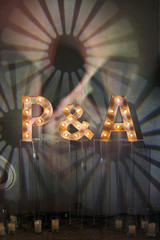 Shiny letters P&A stand on glass vases before the wall