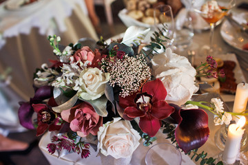 Bouquet of dark orchids and white hydrangeas put on the candleholder