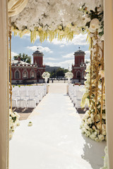 Look from behind wedding altar at white chairs standing in the rows on backyard