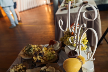 Wooden initials stand on the white table with cheese