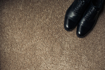 Black leather shoes on brown carpet