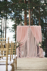 Golden chairs stand on the porch before pink wedding altar