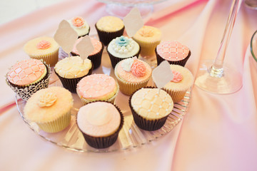 Tasty cupcakes covered with pink glaze stand on glass plate