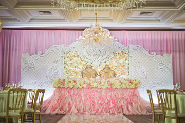 Dinner table for wedding couple covered with pink cloth and white flowers