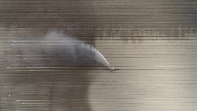 Aerial top down view of irrigation sprinkler distributing water over dry soil during drought period sprinkler system irrigates field and thus it is widely used in sandy areas steady aerial view 4k