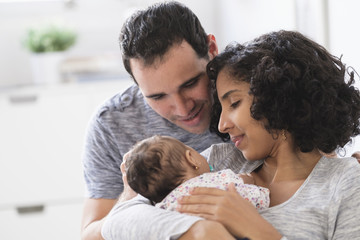 Hispanic mother and father admiring baby daughter