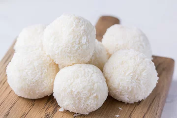 Gordijnen Coconut candy on a wooden board. Round coconut balls © danilsneg