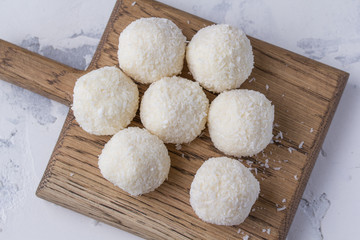 Coconut candy on a wooden board. Round coconut balls