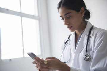 Doctor using smartphone while standing in hospital
