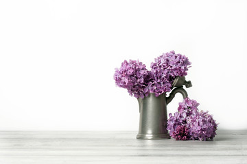 Stylish old kettle,branch of lilac on white background