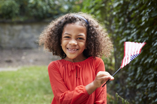 Portrait of smiling Mixed Race girl waving little American flag
