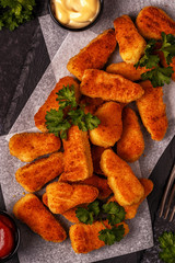 Chicken naggets with sauces on dark background.