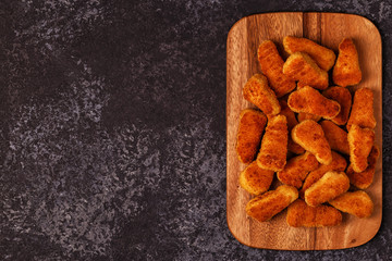 Chicken naggets with sauces on dark background.