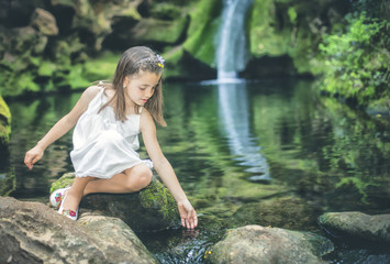 Little girl plays sweetly with water beside the bed of a river