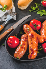 Barbecue. Home hotdogs. Grilled vegetables. sausages, tomatoes and peppers on a grilled baking sheet, cooked. With spices and herbs. With buns bread. On black stone table. Copy space