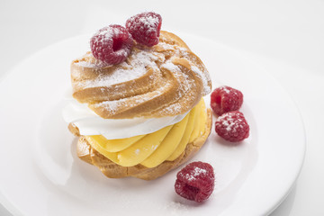 Biscuit cake with raspberry berries on a white plate. On white table.