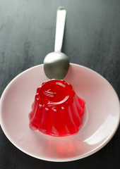 Male hand with spoon eating strawberry jelly.  