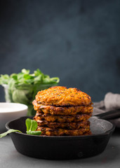 Sweet potato fritters in iron skillet served with fresh green salad and yogurt sauce
