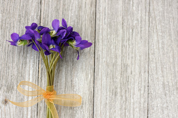 Small bouquet of violets on a wooden background