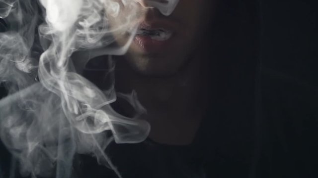 young vaper man exhaling big clouds of smoke with e-cigarette vape in slowmotion
