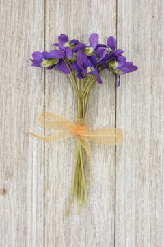 Small bouquet of violets on a wooden background