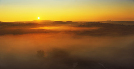 Fototapeta na wymiar Foggy hill in autumn shot at sunrise