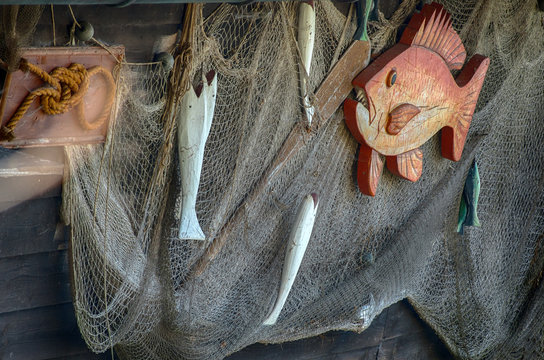 Fishing net the wall of a cabin with hanged decorative wooden fishes on it.