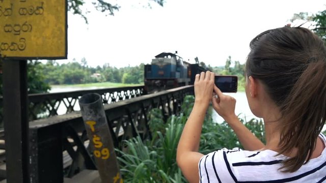 Woman taking photo of old train riding on bridge in Sri Lanka, super slow motion 240fps
